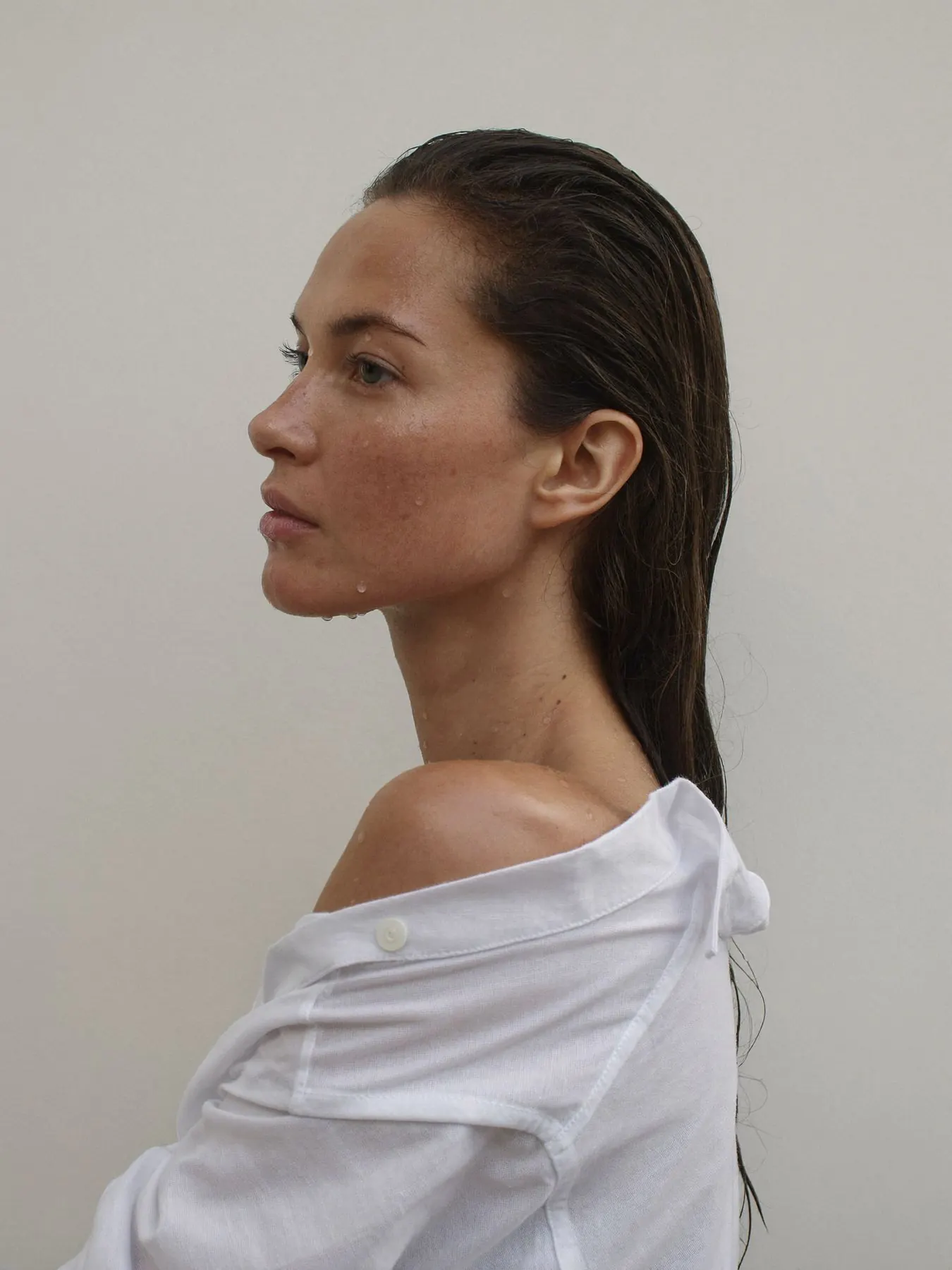 Retrato de perfil de una mujer con el pelo mojado y camisa blanca