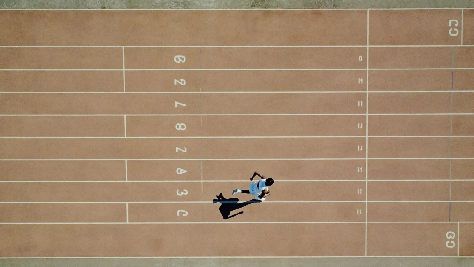 Vista aérea de una pista de atletismo con un corredor solo